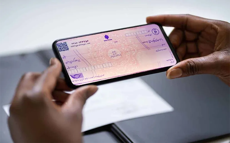 مردی که گوشی در دست دارد و از چک بانکی عکس می گیرد